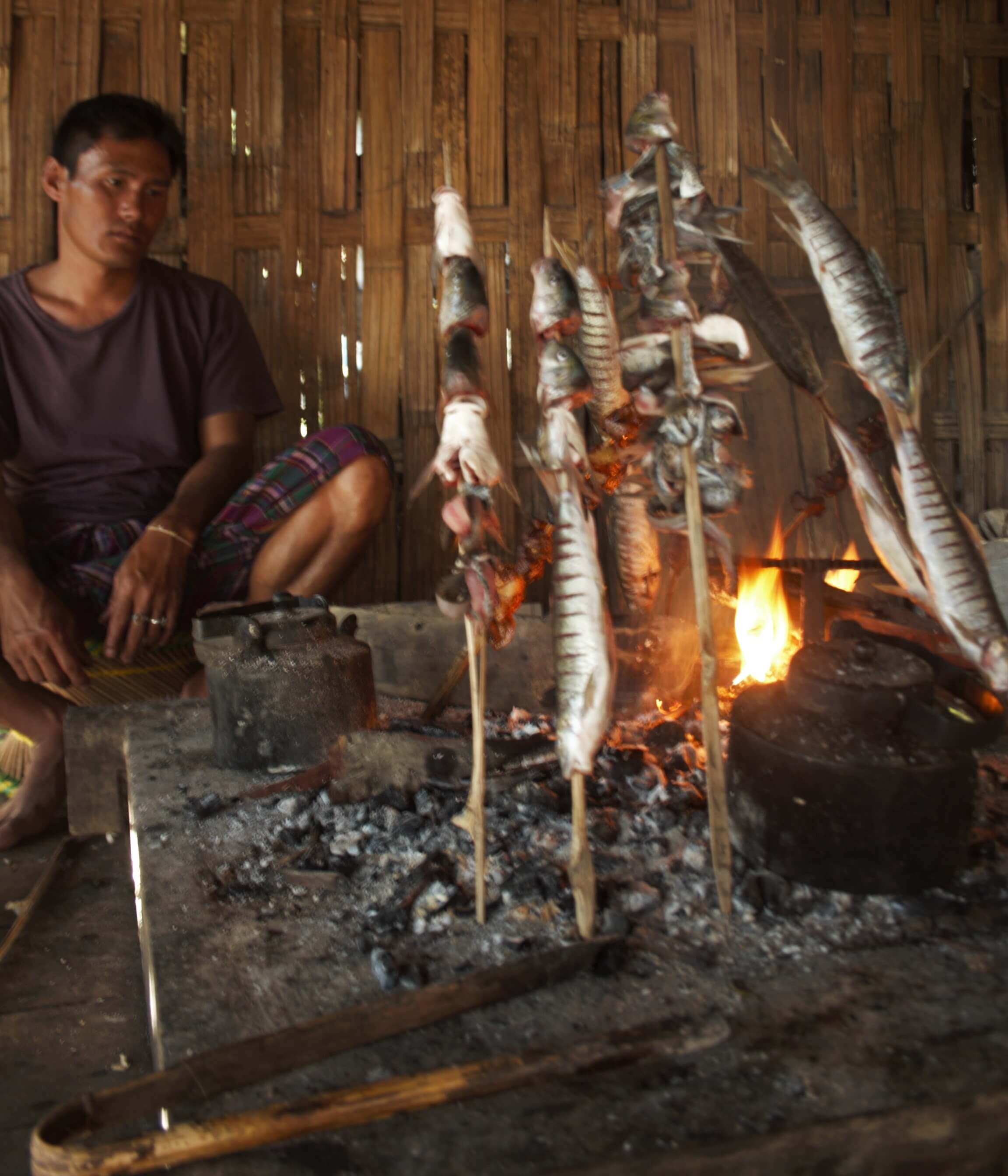 A local man preparing fish by the fire